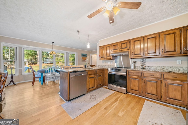 kitchen featuring pendant lighting, appliances with stainless steel finishes, light hardwood / wood-style floors, a textured ceiling, and kitchen peninsula