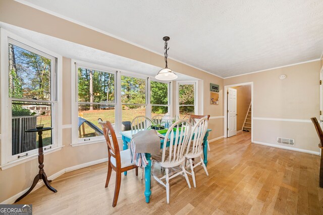 dining area with ornamental molding and light hardwood / wood-style floors