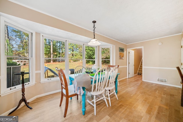 dining area with crown molding and light wood-type flooring