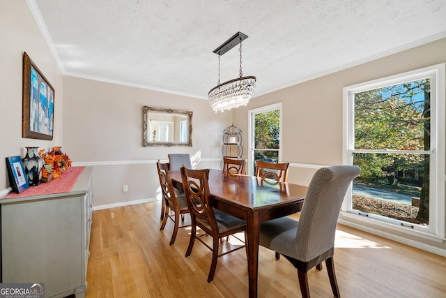 dining space featuring crown molding, light hardwood / wood-style floors, a textured ceiling, and a notable chandelier