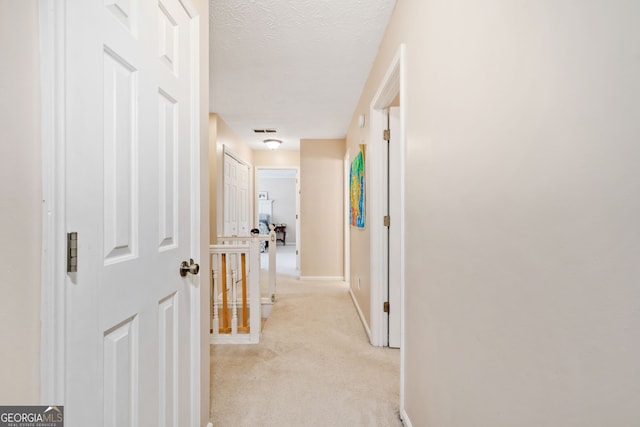 hall featuring light carpet and a textured ceiling