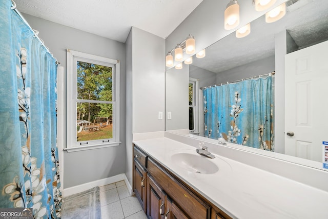 bathroom featuring plenty of natural light, tile patterned flooring, vanity, and a textured ceiling