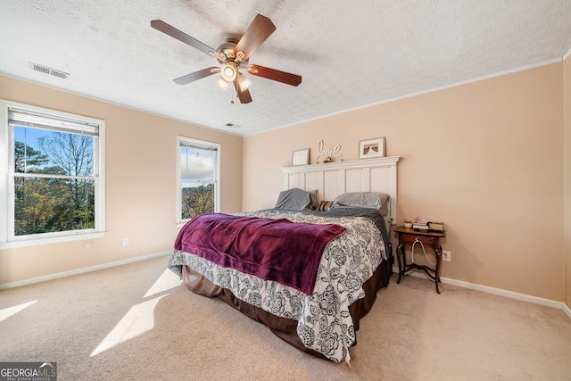 bedroom with light carpet, ceiling fan, and a textured ceiling