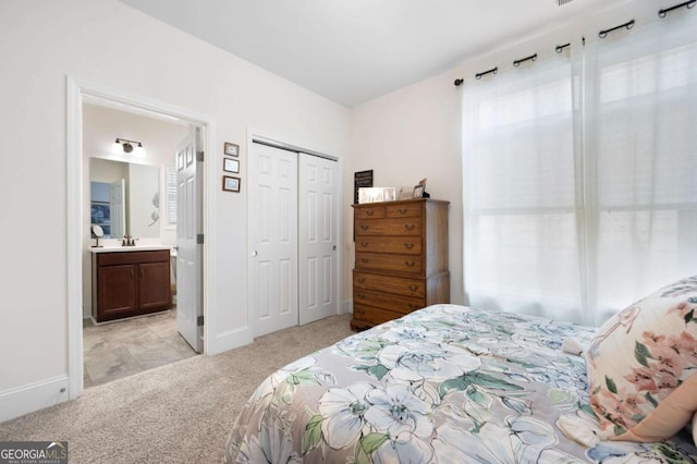 bedroom featuring ensuite bath, light colored carpet, and a closet