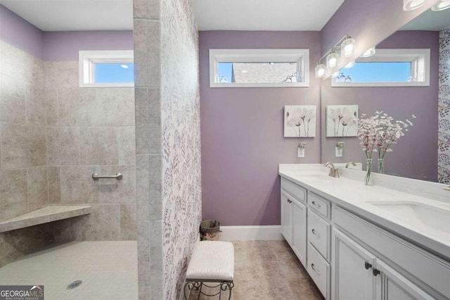 bathroom with a wealth of natural light, a tile shower, and vanity