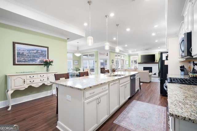 kitchen featuring stainless steel appliances, sink, hanging light fixtures, dark hardwood / wood-style floors, and a kitchen island with sink