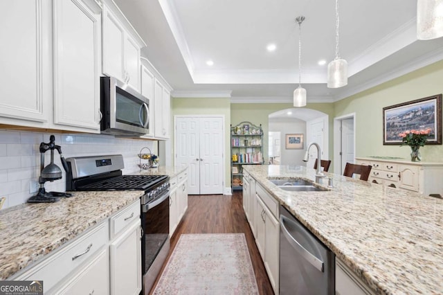 kitchen featuring stainless steel appliances, white cabinetry, decorative light fixtures, and sink