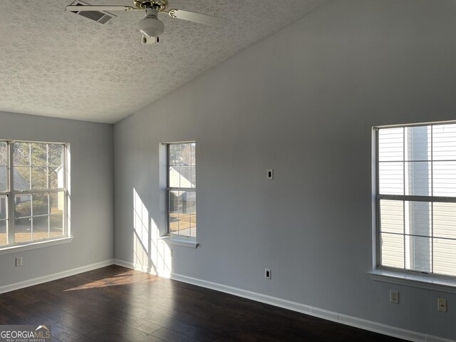 empty room featuring ceiling fan, vaulted ceiling, dark wood-type flooring, and a textured ceiling