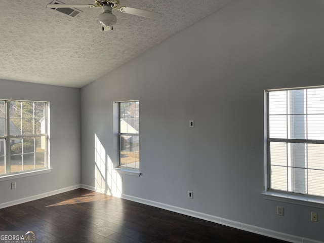 spare room featuring lofted ceiling, plenty of natural light, a textured ceiling, and hardwood / wood-style floors