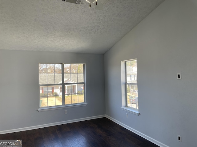 unfurnished room with a wealth of natural light, dark wood-style flooring, vaulted ceiling, and baseboards