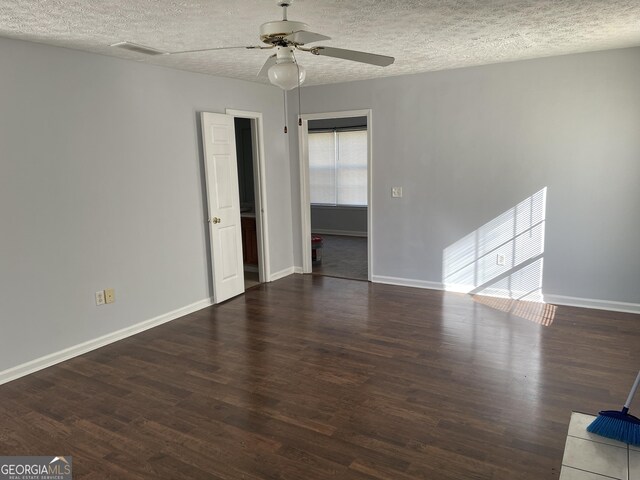 spare room with ceiling fan, a textured ceiling, and dark hardwood / wood-style flooring