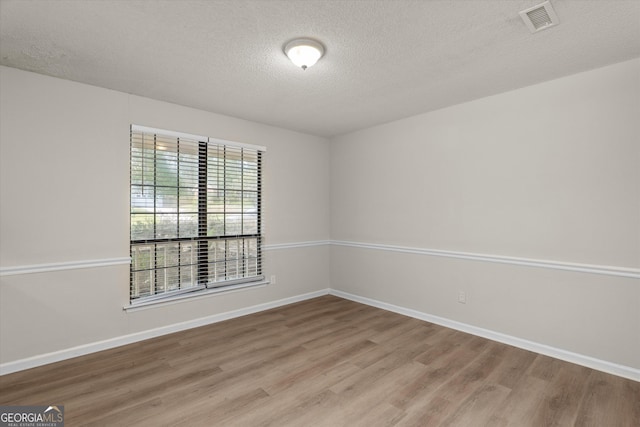 empty room with a textured ceiling and light hardwood / wood-style floors