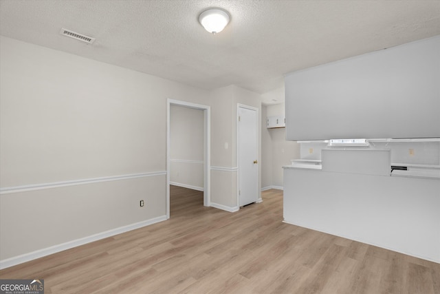 unfurnished living room featuring light wood-type flooring and a textured ceiling