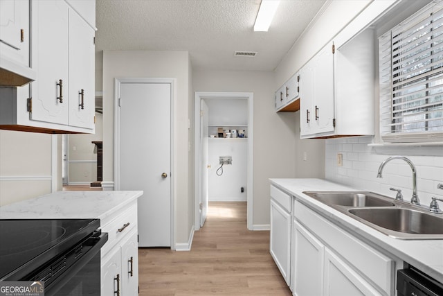 kitchen with dishwashing machine, a textured ceiling, white cabinets, sink, and backsplash