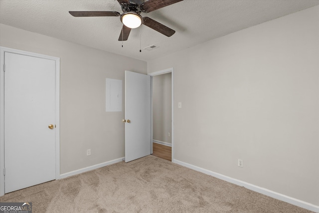 unfurnished bedroom featuring ceiling fan, light colored carpet, and a textured ceiling