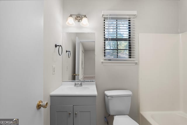 bathroom with toilet, vanity, and a tub to relax in