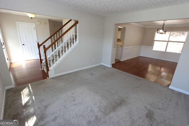 unfurnished living room featuring a textured ceiling, ornamental molding, and dark carpet