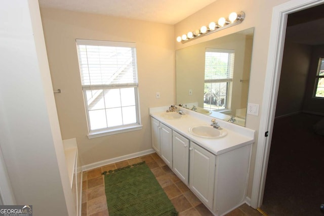 bathroom featuring a tub to relax in, vanity, and a healthy amount of sunlight