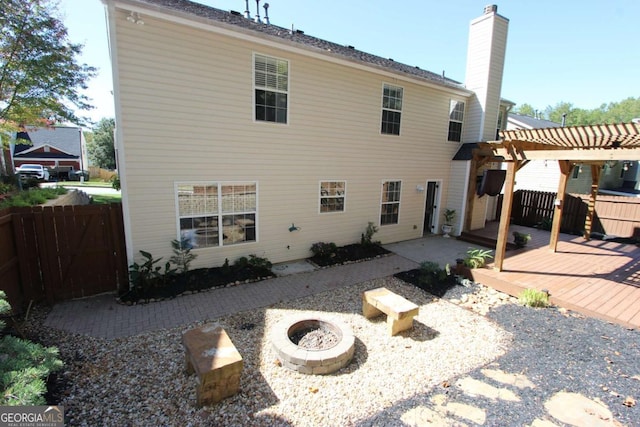 back of house featuring a pergola, a deck, an outdoor fire pit, and a patio