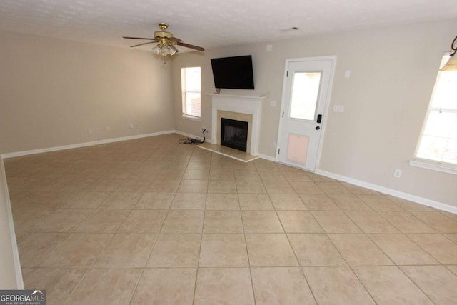 unfurnished living room with a textured ceiling, ceiling fan, and light tile patterned flooring