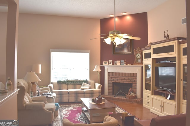 living room featuring a textured ceiling, ceiling fan, a high ceiling, a fireplace, and wood finished floors