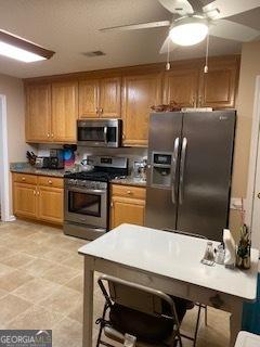 kitchen featuring stainless steel appliances, a ceiling fan, and brown cabinets