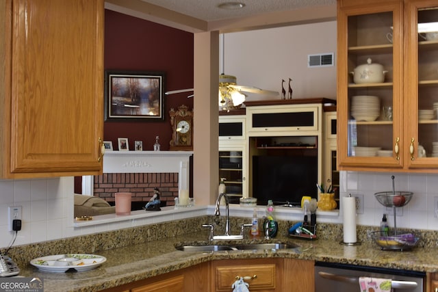 kitchen with stainless steel dishwasher, stone counters, visible vents, and a sink