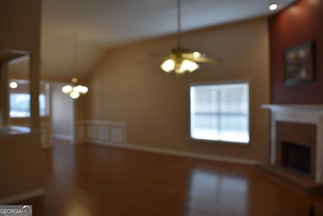 unfurnished living room with a fireplace with raised hearth, ceiling fan, and vaulted ceiling