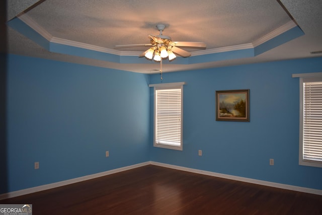 spare room with a ceiling fan, ornamental molding, dark wood-type flooring, a tray ceiling, and a textured ceiling