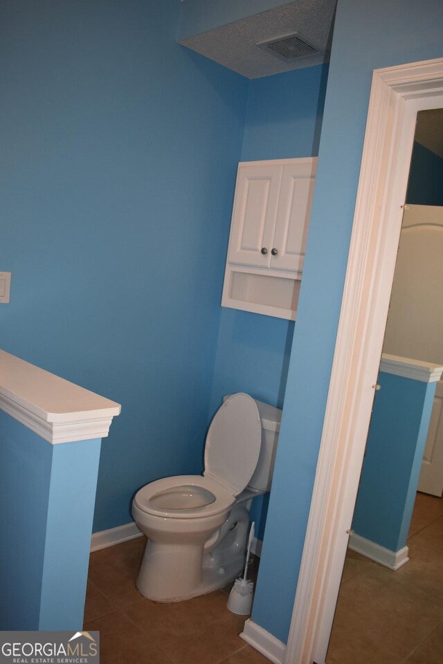 bathroom featuring toilet, tile patterned flooring, visible vents, and baseboards