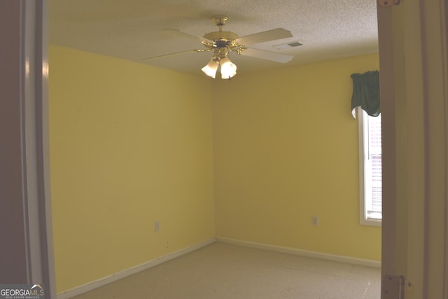 spare room featuring a textured ceiling, ceiling fan, visible vents, and baseboards