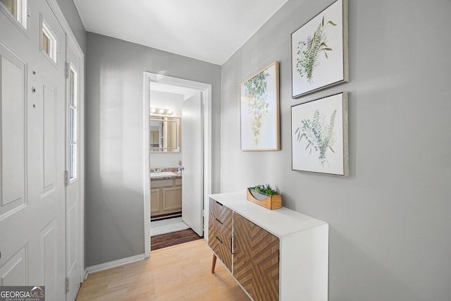 corridor featuring light wood-type flooring and sink