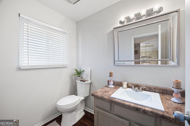 bathroom with toilet, vanity, and wood-type flooring