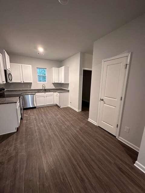 kitchen featuring dishwasher, sink, white cabinetry, dark wood-type flooring, and range