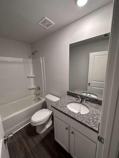 full bathroom with toilet,  shower combination, hardwood / wood-style floors, and vanity