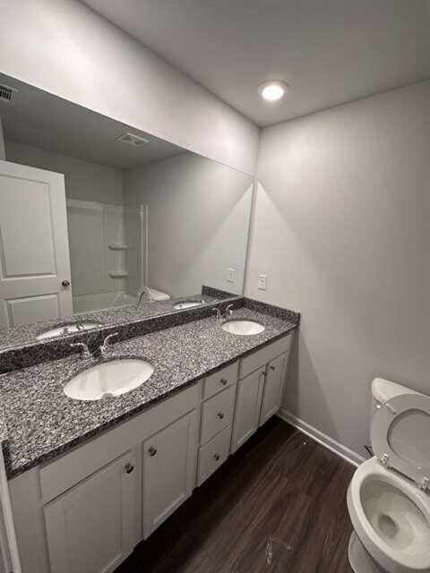 bathroom featuring toilet, vanity, walk in shower, and hardwood / wood-style floors