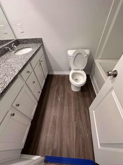 bathroom with toilet, hardwood / wood-style floors, and vanity