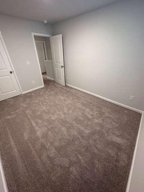 unfurnished bedroom with dark carpet