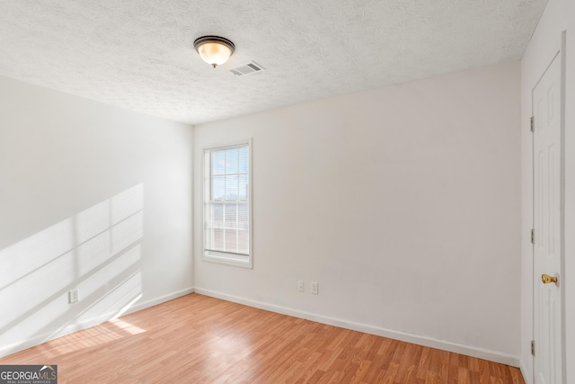 unfurnished room featuring a textured ceiling and light hardwood / wood-style flooring