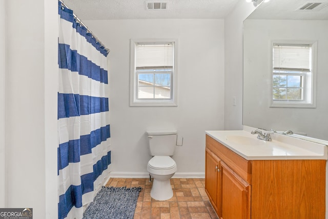 bathroom with vanity, a wealth of natural light, a textured ceiling, and toilet