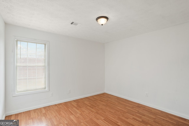 unfurnished room featuring wood-type flooring and a textured ceiling