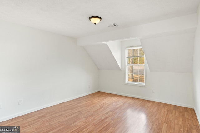 additional living space featuring vaulted ceiling and light hardwood / wood-style floors