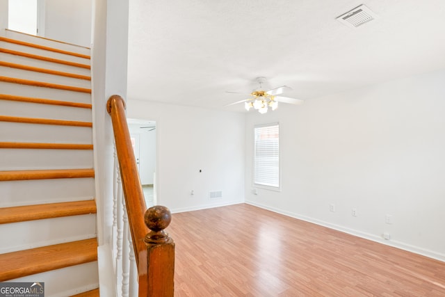 stairway featuring hardwood / wood-style flooring and ceiling fan