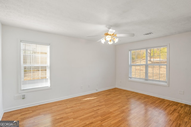 empty room with hardwood / wood-style floors, a textured ceiling, and ceiling fan