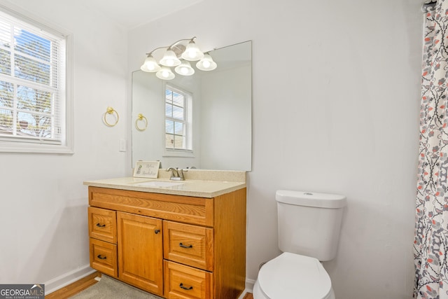 bathroom featuring vanity, a healthy amount of sunlight, toilet, and an inviting chandelier