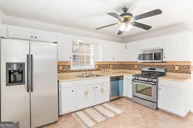 kitchen featuring sink, appliances with stainless steel finishes, white cabinetry, backsplash, and light tile patterned flooring