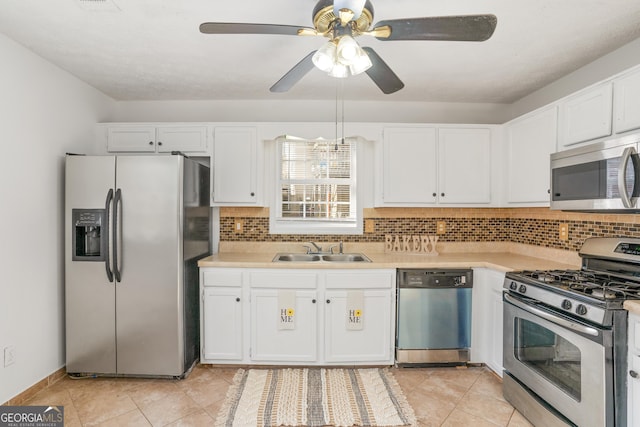 kitchen with appliances with stainless steel finishes, sink, decorative backsplash, and white cabinets