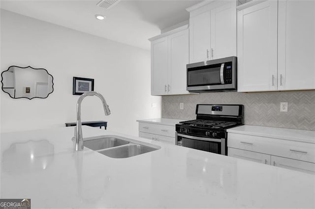 kitchen featuring appliances with stainless steel finishes, backsplash, white cabinetry, and sink