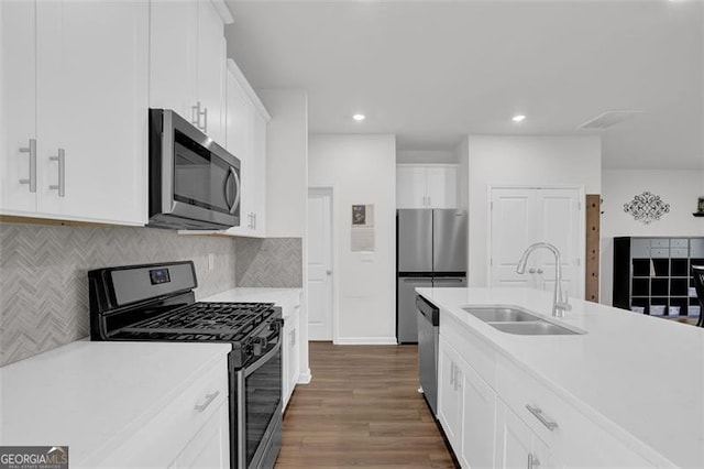 kitchen with dark hardwood / wood-style floors, decorative backsplash, sink, stainless steel appliances, and white cabinets