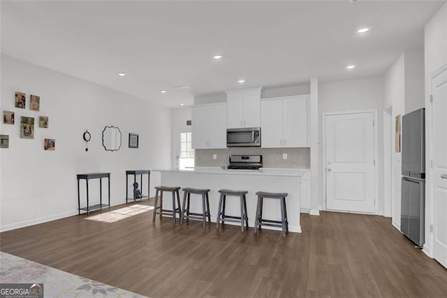 kitchen featuring a kitchen bar, stainless steel appliances, dark hardwood / wood-style flooring, a kitchen island, and white cabinets